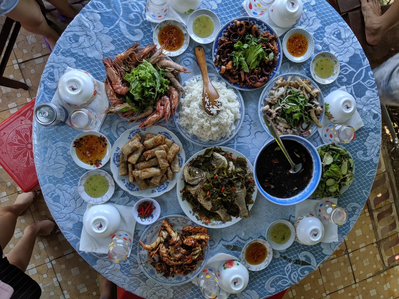 Mâm cơm tại Sơn Tiệm Homestay bày trên bàn tròn: tôm hấp, mực xào, ghẹ, chả ram, cá, rau xào và cơm trắng